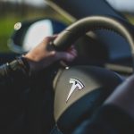 person holding black Tesla steering wheel